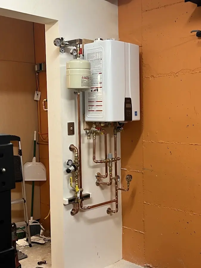 Plumbing technician inspecting water heater connections in Lowell